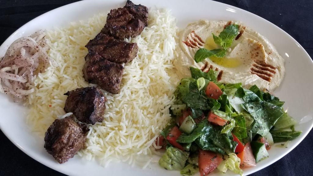 Beef Kabob Plate · 6 pieces of beef kabob served on a bed of rice alongside a serving of house salad, hummus, and bread.