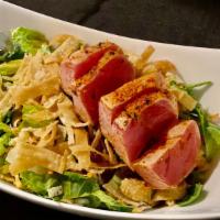 **Seared Ahi Salad · Slices of seasoned seared ahi tuna, placed over a bed of spring greens and Asian slaw, tosse...