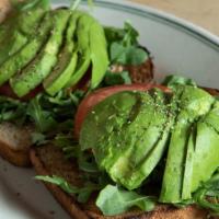 Avocado Toast · Our bread topped with a whipped avocado-sour cream spread, arugula, sliced tomato, cracked b...