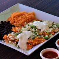 Chilaquiles Con Huevo · Corn tortillas cooked with green or red sauce. Fresh cheese, sour cream, diced onions, and c...