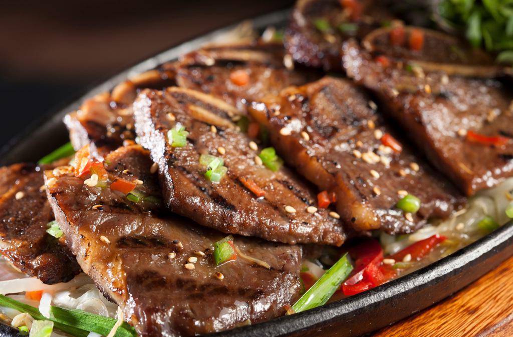 Galbi (9pcs) · Grilled marinated beef short ribs over sautéed mushrooms, bell peppers & onions, topped with green onions & sesame seed.
