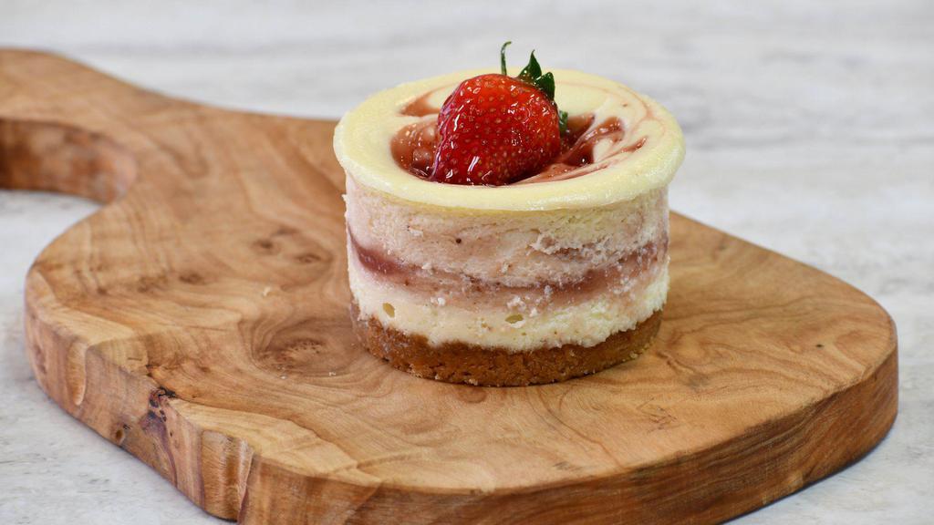 Strawberry Fields Cheesecake · Creamy vanilla filling with house-made organic strawberry purée of fresh organic California grown sweet strawberries and topped with sliced strawberries.