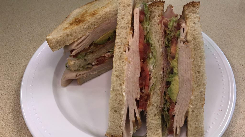 Gone Clubbin' · Triple-decker sandwich on toasted sliced sourdough bread with turkey, bacon, avocado, lettuce, tomato, and mayonnaise.