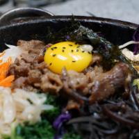 Dolsot Bibimbap · Assorted vegetables served over rice crisped over the fire with a fried egg .