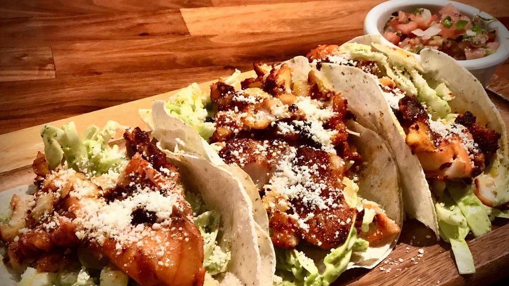 Fish Tacos · local wild rockfish marinated Yucatan-style and grilled ala plancha.  Cilantro slaw, chipotle aioli, cotija cheese, pico de gallo. Regular order comes with 2 tacos.  Image shown shows 3 ($7 each additional taco)
