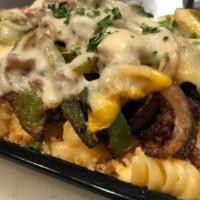 Philly Mac N' Cheesesteak · Our big cheezis piled with sautéed onions, peppers, seared thinly sliced steak, provolone, a...