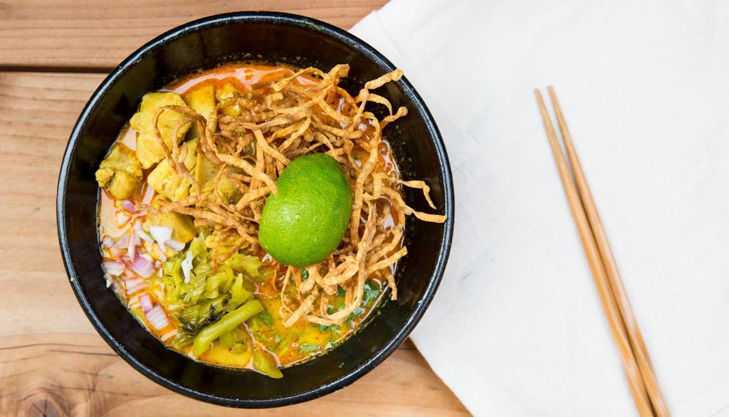 Khao Soi Gai · Northern Thai-style curry, egg noodle, chicken, pickled mustard, shallot, cilantro, fried ground chillies, crispy noodle, and lime.