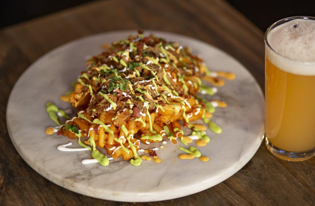 Drunken Pig Fries · Waffle fries, covered in melted mixed cheese, beer-braised pulled pork, spicy jalapeño salsa, spicy ranch, sour cream, cilantro and bacon bits.