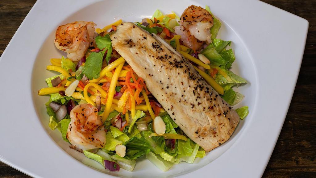 Thai Mango Salad W/ Grilled Mahi & Prawns · Shredded sweet mangos, red onion, green onion, cilantro, baked coconut flakes, and toasted almonds, in a citrus Thai vinaigrette topped with grilled mahi & grilled prawns