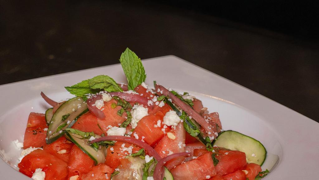 Watermelon Salad · Freshly cut watermelon, cucumber, mint, basil, pickled red onion, all tossed in house made citrus vinaigrette. Topped with feta cheese crumbles.