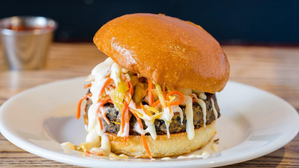 Manassa Mauler Burger · Vegetarian. Hand made black bean patty with jalapeño slaw and sweet chilli aioli. Served with lettuce, tomatoes, house-made garlic and infused aioli. Cooked medium.