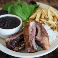Costillas de Cerdo · Rotisserie pork ribs served with salad, rice, beans, and plantains.