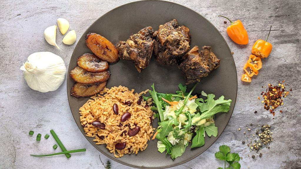 Oxtail Plate · Braised Oxtail marinated in spicy jerk seasoning. Served with sides of fried sweet plantains, rice and kidney beans and salad. Accompanied by mango citrus dressing and jerk sauce.
