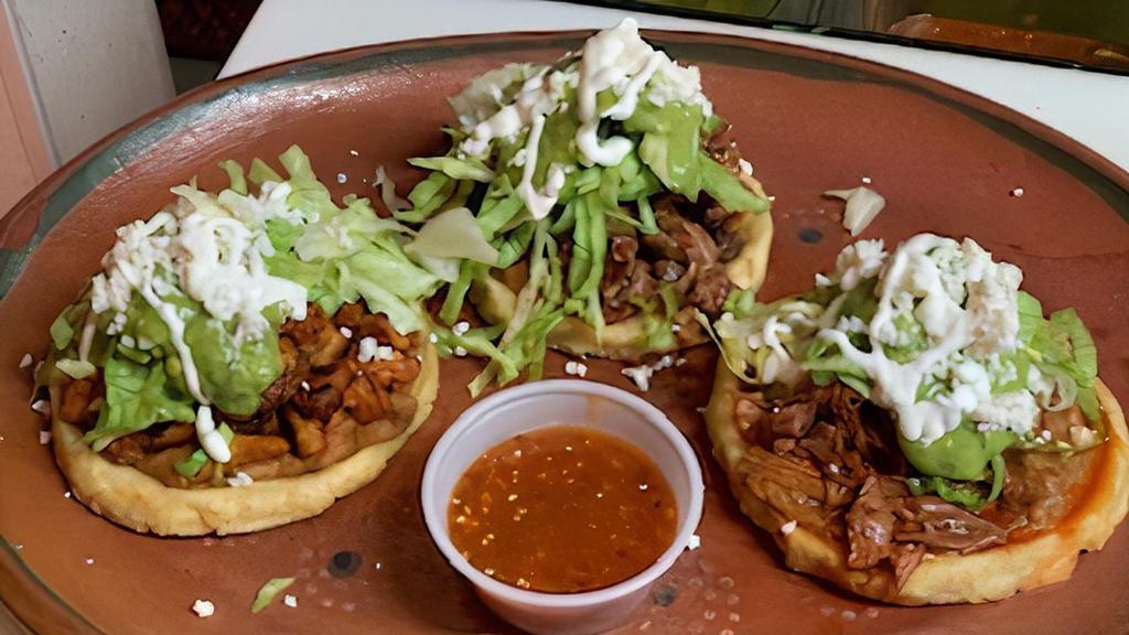3 Sopes · Includes one beef, one al pastor, one birria, with beans, lettuce, queso fresco, and tomatillo sauce, sour cream.