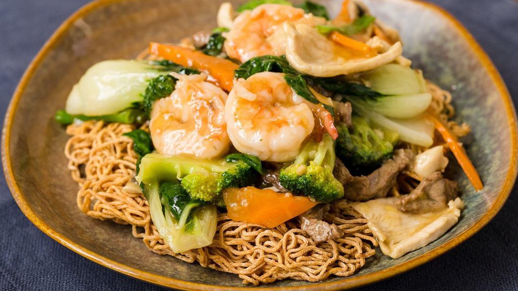 Hong Kong Noodles · Prawns, flank steak, chicken, bok choy, carrots, broccoli, scallions, and mushrooms over a cripsy noodle bed.