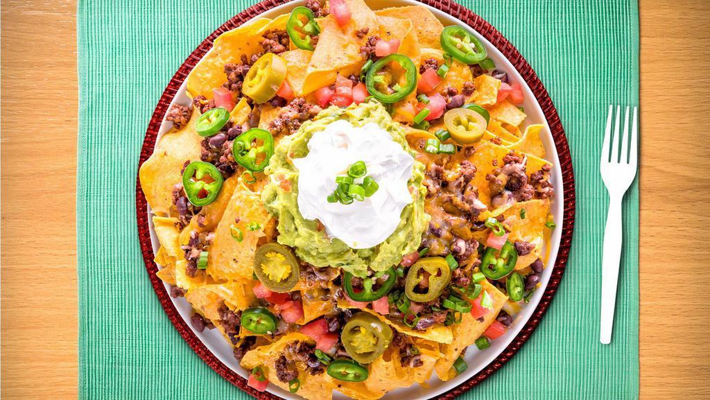 Super Nachos · Plate of fried tortilla chips covered in ground beef or chicken with shredded cheese, beans, tomatoes, sour cream, green onions.