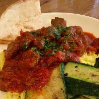 Lamb Kapama · Braised lamb in a tomato sauce with cinnamon, Served over rice with grilled vegetables and p...