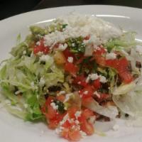 36. Tostada · Fried corn tortilla topped with beans. Choice of meat, cheese, beans, lettuce, guacamole, so...