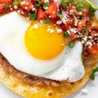 Huevos Rancheros · Two fried eggs served on a layer of black bean puree and crispy corn tortillas, topped with ...