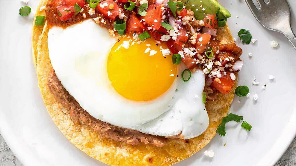 Huevos Motuleños · Two fried eggs, sliced ham, plantains and a layer of black bean puree on crispy corn tortillas, topped with salsa, sour cream and pico de gallo.