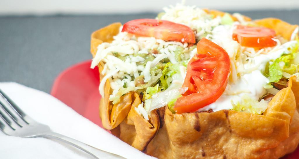 Veggie Taco Salad · Fried flour tortilla shell topped with rice, choice of beans (pinto, whole or black beans), lettuce, guacamole, sour cream, Monterey Jack cheese and tomatoes.