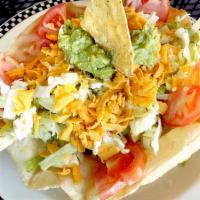 Taco Salad · Crisp tortilla chips, taco meat, beans, guacamole, sour cream and tomatoes on a bed of shred...