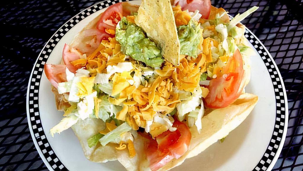 Taco Salad · Crisp tortilla chips, taco meat, beans, guacamole, sour cream and tomatoes on a bed of shredded lettuce