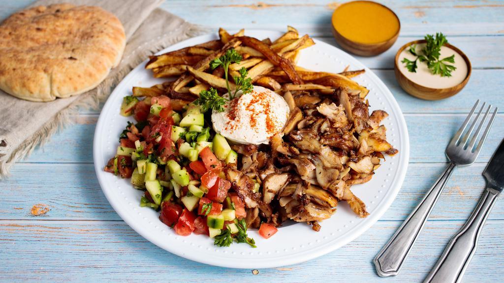 Shawarma Plate · Rotisserie fired chicken & lamb thinly sliced, served with hummus, tahini, Israeli salad, rice and a pita.