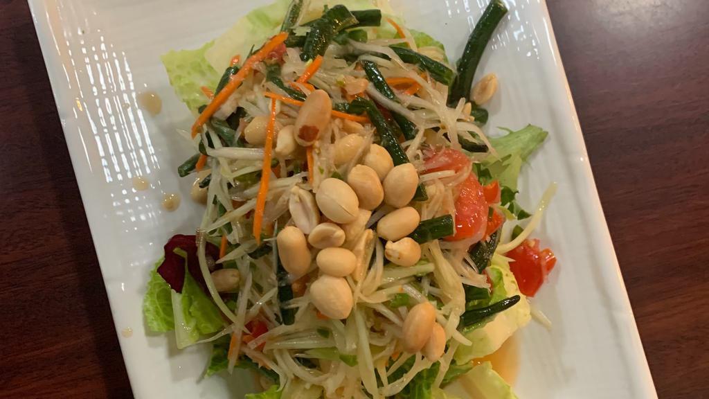 10. Papaya Salad · Shredded green papaya with tomatoes, green bean, ground peanuts, dried shrimps in spicy lime dressing, and served with sliced cabbage.