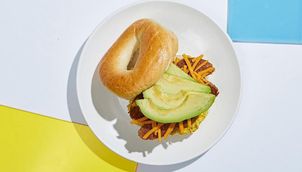 Vegan Breakfast Bagel · Scrambled tofu with vegan sausage, sliced avocado, and vegan cheese on a toasted bagel.