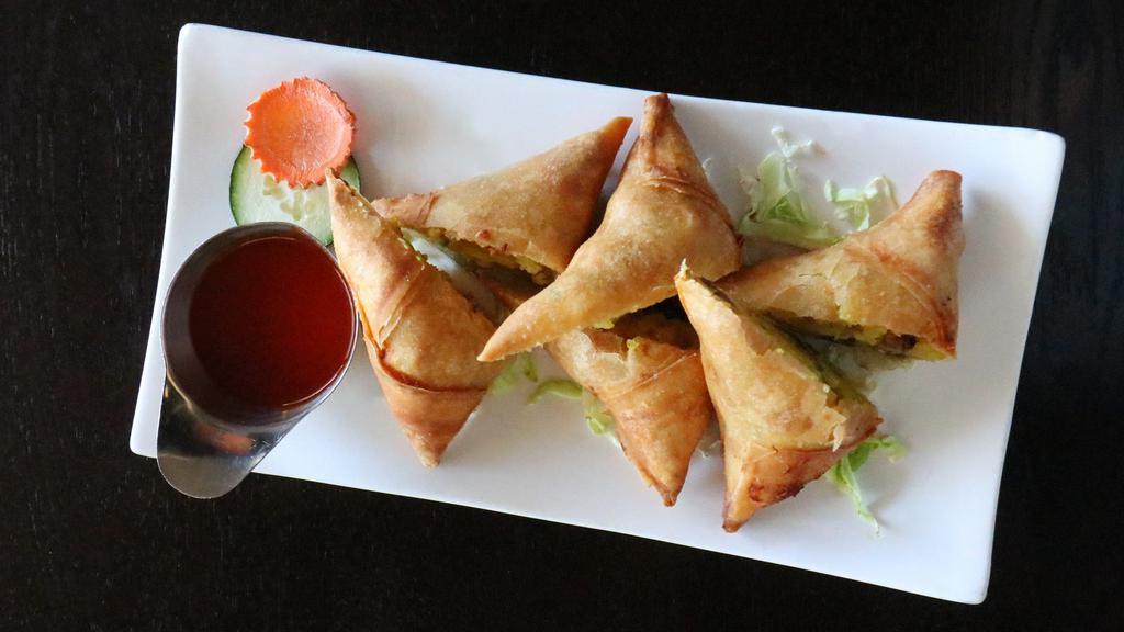 Burmese Samusas · Hand-folded and wrapped curry puff filled with potato, onion, jalapeno, and turmeric seasoning accompanied with a chili sauce.