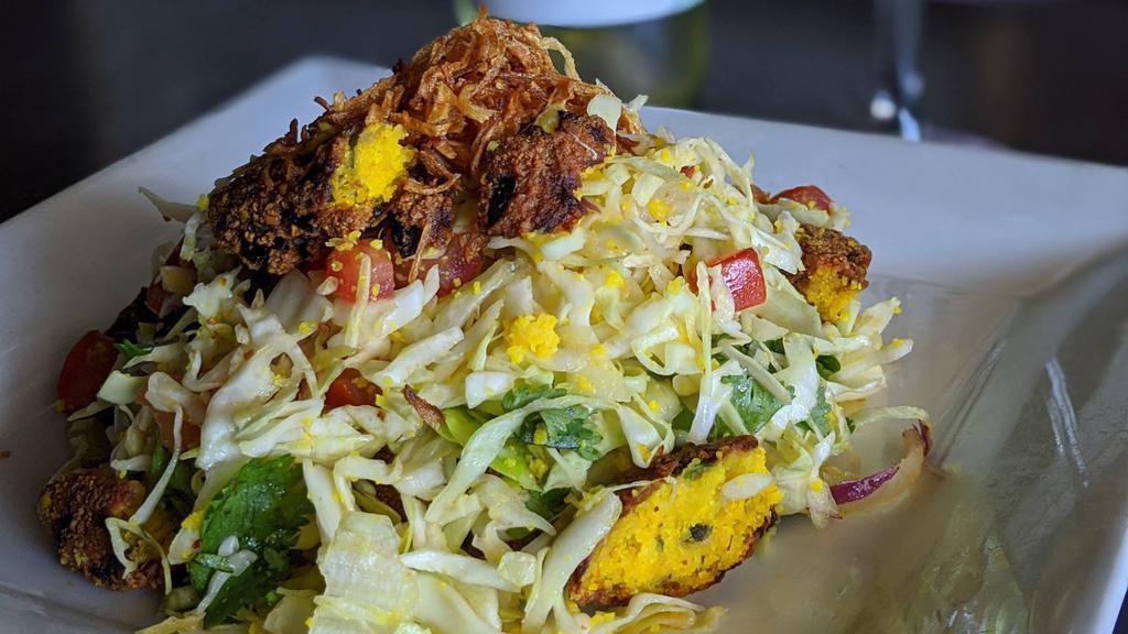 Burmese Falafel Salad · Handmade Burmese falafels containing split yellow peas, onion, and mint all mixed together with red onions, cilantro, tomatoes, lime, fried onion