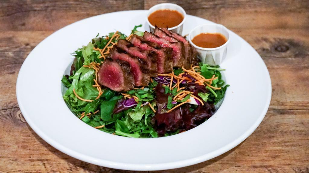 Thai Beef Salad · Mixed greens topped with strips of grilled, marinated Thai beef, carrots, cilantro, red cabbage, green onions and crispy Asian rice noodles with a sweet and spicy Thai peanut dressing.