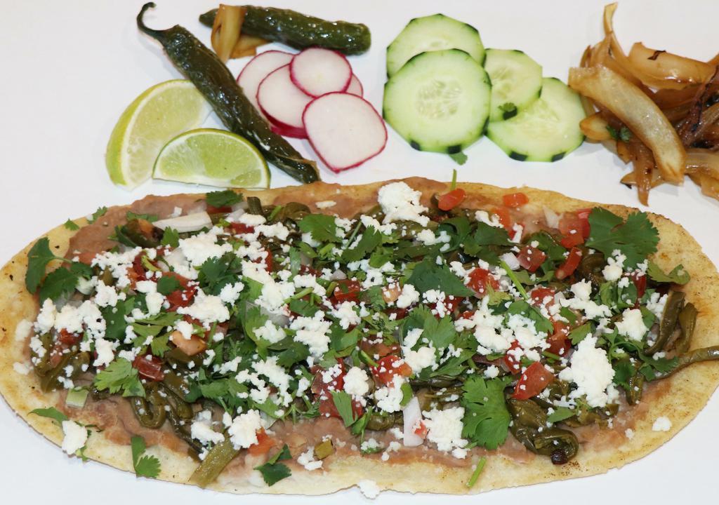 Huarache · Huarache is a popular Mexican dish consisting of corn masa dough with smashed, it is given an oblong shape. Refried smash beans, your choice of meats, shredded lettuce, diced tomato, queso fresco (Mexican fresh cheese), sour cream, onions, cilantro, salsa, and sliced radishes for garnish.