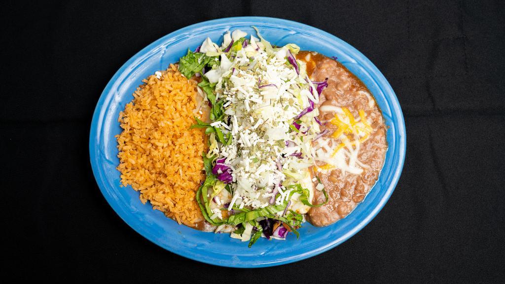 Enchiladas Rancheras · Two corn tortillas dipped in red sauce and grilled with choice of ground beef, chicken or pork, then topped with lettuce, cabbage, cheese, oregano, onions and sauce. Served with refried beans and rice.