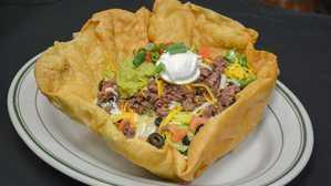 Taco Salad · Crisp mixed greens tossed with our chipotle ranch dressing, topped with seasoned ground beef...