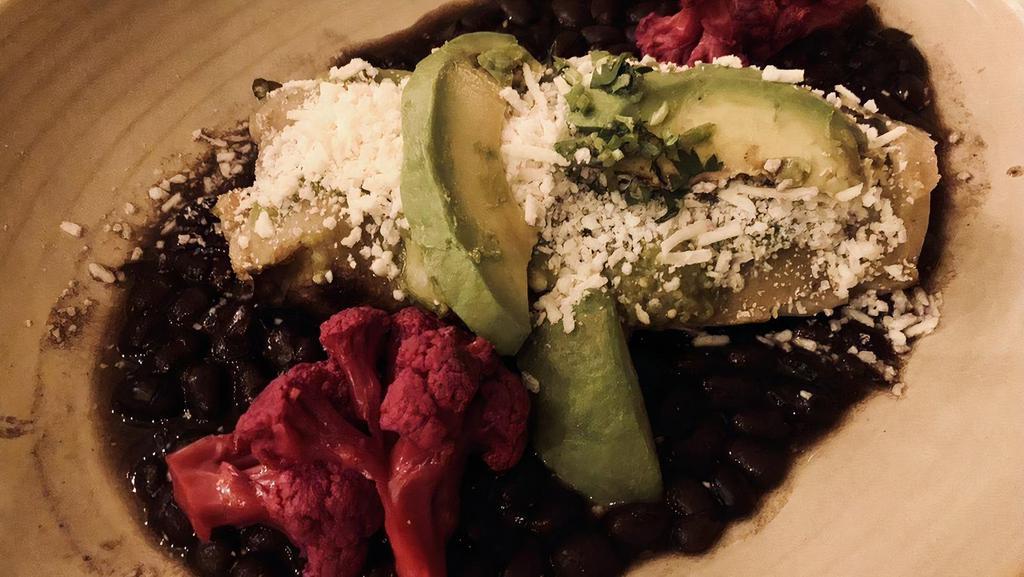 Tamal Chilango · 1 large tamale, shredded chicken, black beans, avocado slices, tomatillo and epazote salsa, served on banana leaves.