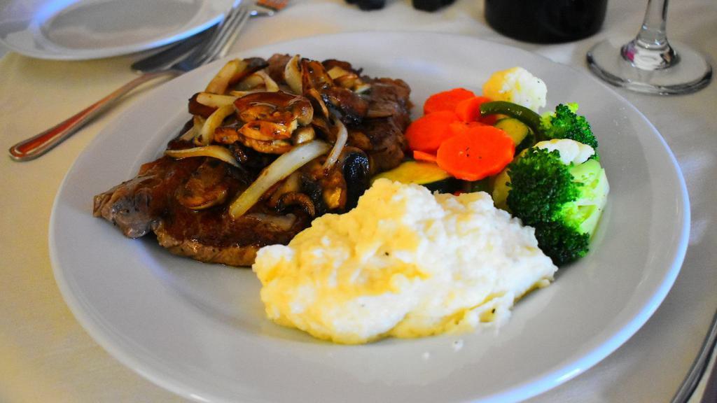 Bistecca di Ribeye · Grilled ribeye steak topped with sauteed mushrooms & onions. Served with vegetables & garlic mashed potatoes.