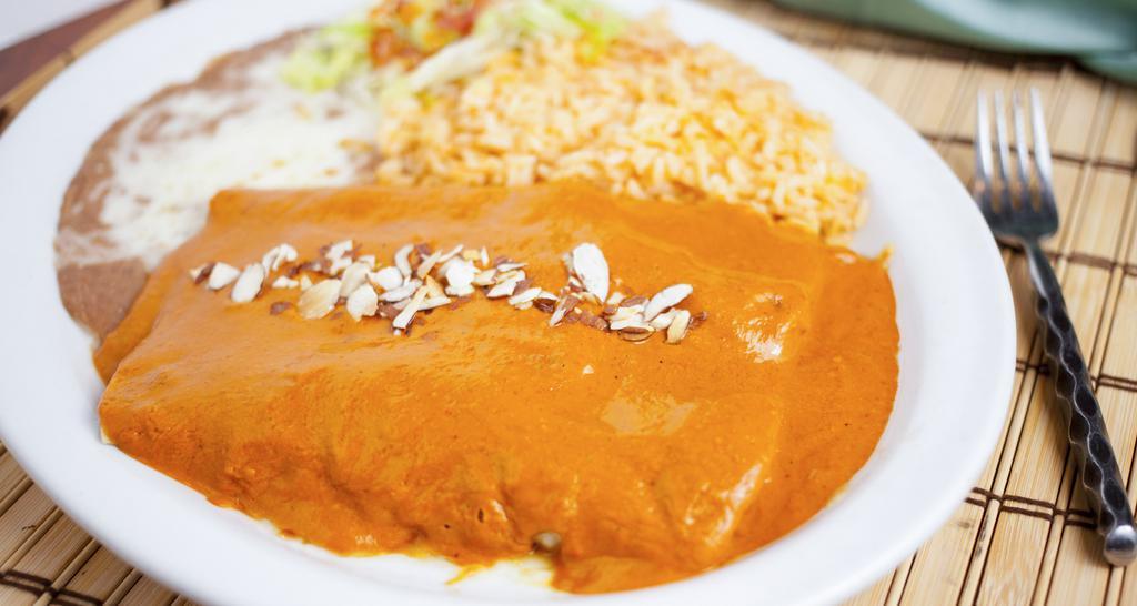 Enchiladas El Caminito · Two enchiladas filled with chicken breast, topped with melted cheese and el caminito sauce (sour cream, chile guajillo, and spices) and almonds.