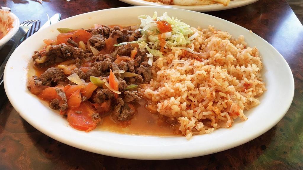 Steak or Chicken Ranchero · Slices of skirt steak or chicken simmered with our own special sauce with bell peppers, onions, tomatoes, and hot peppers. Served with rice and beans.