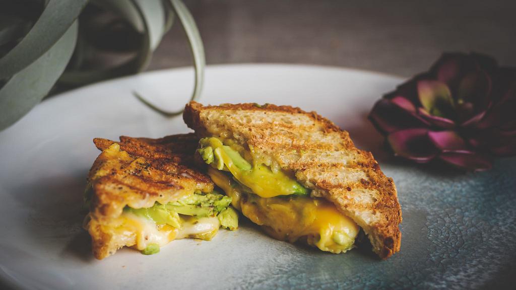 Avocado Grilled Cheese · Gluten-free bread, mayo, organic cheddar cheese, organic pepper jack cheese, pickled carrots, and avocado. Served with green sauce on the side.