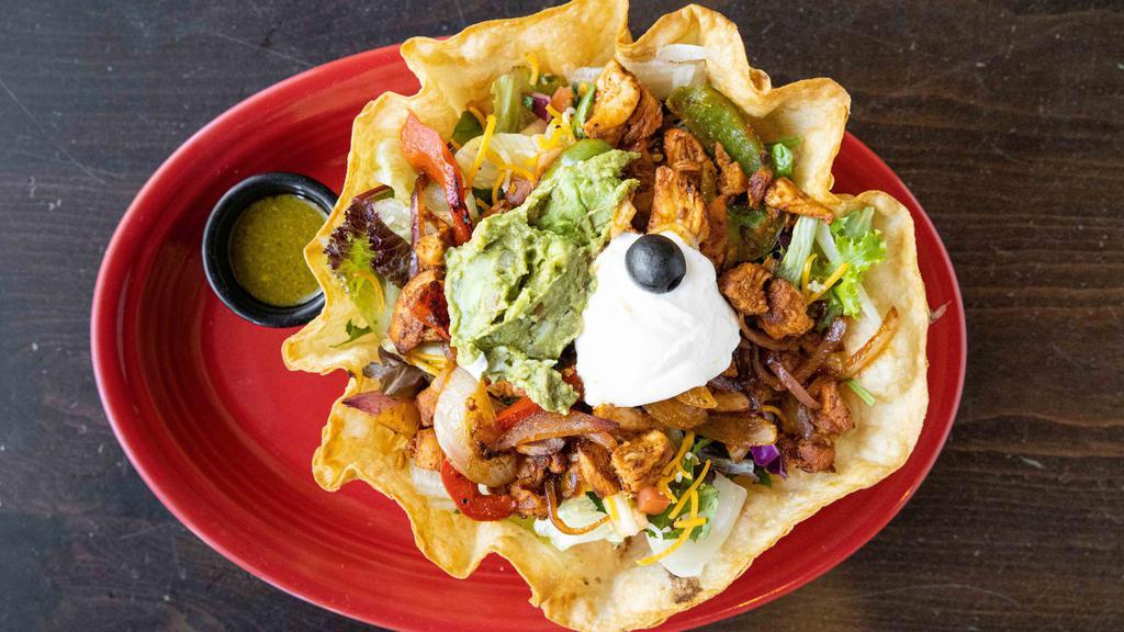 Fajitas Tostada Salad · Tortilla shell filled with warm black beans, lettuce, tomatoes, grilled chicken breast, cheese, salsa fresca, sour cream, sauteed onions, bell peppers and guacamole.