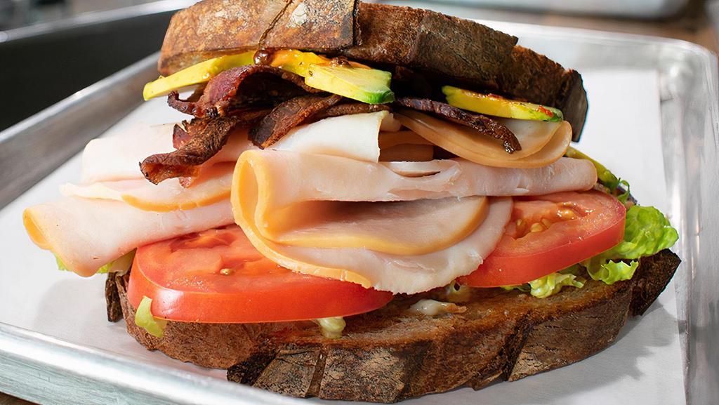 The Club · Sliced Turkey Breast, Bacon, Avocado, Lettuce, Tomato, Red Onion And Roasted Garlic Aioli On Sourdough W/ Choice Of House Chips Or Side Salad