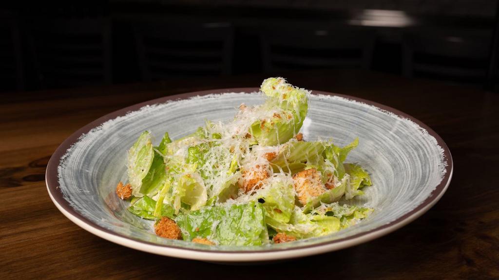 Caesar Salad  · A bed of Romaine, dressed with our house Caesar dressing, garlic croutons and Grana Padano cheese (v)