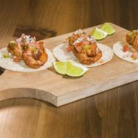 Shrimp Tacos · Seared shrimp on corn tortillas, topped with spicy slaw, chipotle crema, salsa verde and pic...
