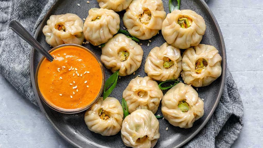 Veggie Momo · Vegan steamed dumpling (cabbage, carrot, onion, spring onion, chives, potatoes, cauliflower with Indian Spices) comes with tomato sesame chutney.