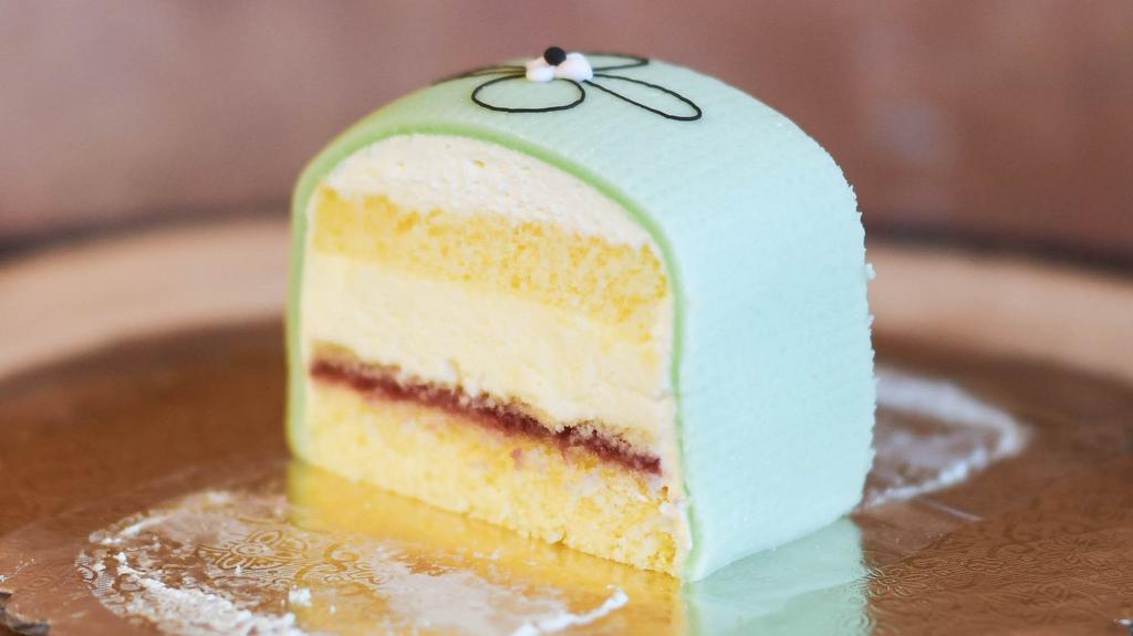 Swedish Princess Cake Slice · Our Swedish Princess is a light vanilla sponge cake with raspberry jam, custard, and whipped cream covered with almond marzipan. It’s one of our most popular cakes!