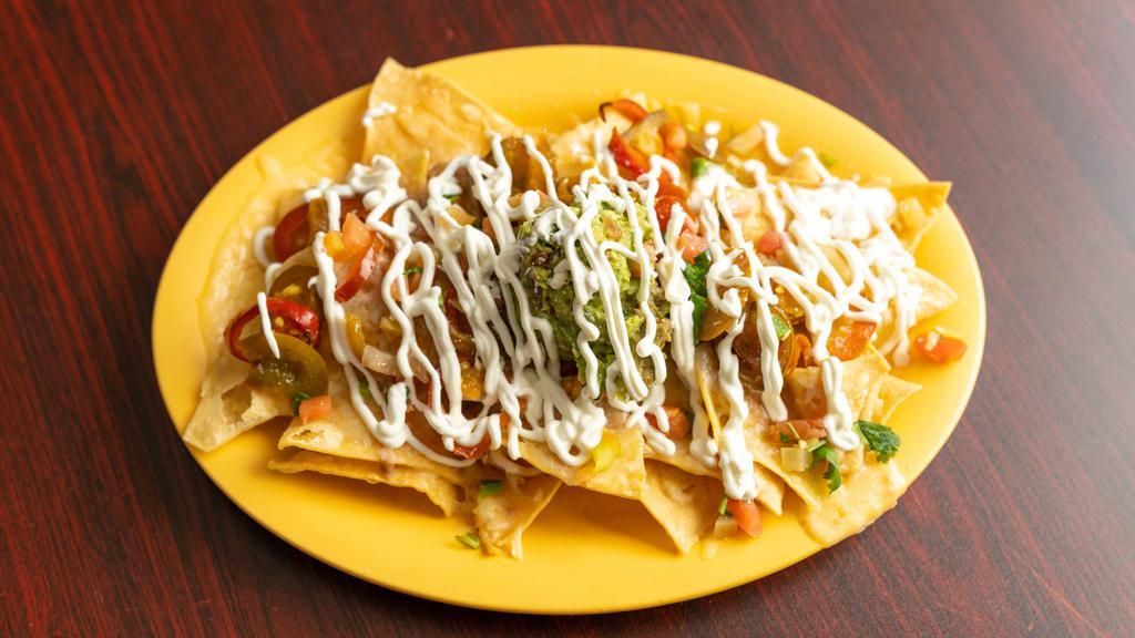 Super Nachos · Chips, choice of meat, choice of beans, guacamole, sour cream, cheese, jalapenos, and pico de gallo on top.