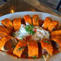 Beyti · Seasoned beef and lamb wrapped in flatbread, topped with yogurt and tomato sauce.