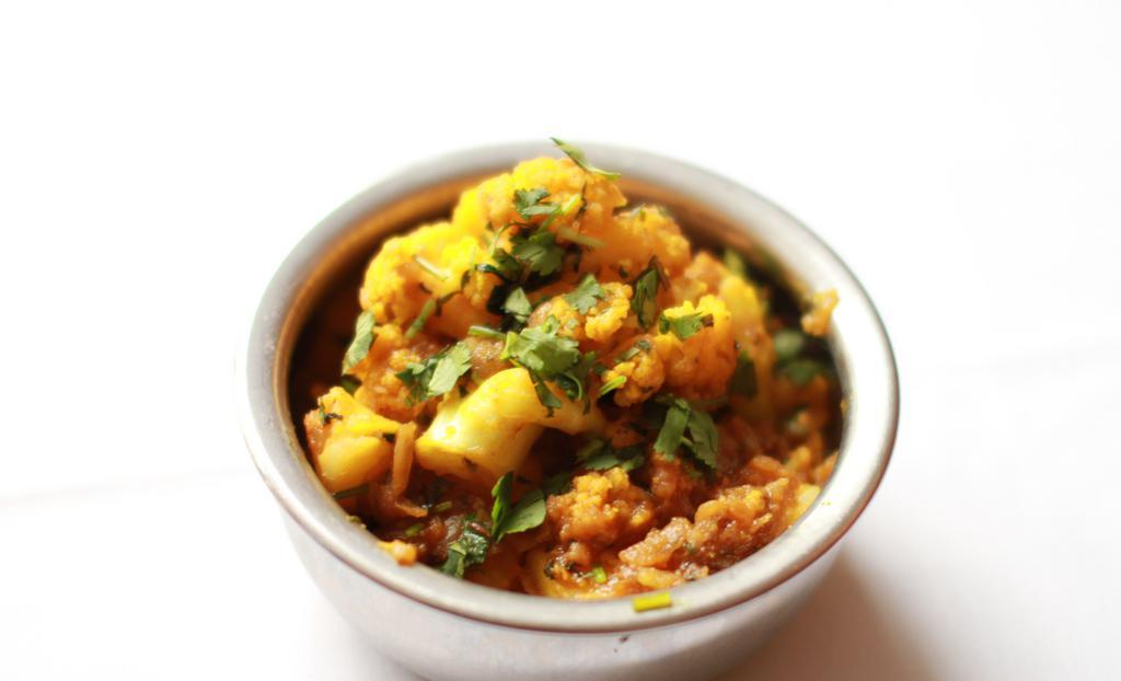 Kashmiri Aloo Gobhi · Fresh cauliflower and white potatoes cooked in kashmiri style with fresh mint leaves herbs, yellow and red onions, ginger, garlic and vine ripened tomatoes and spices.